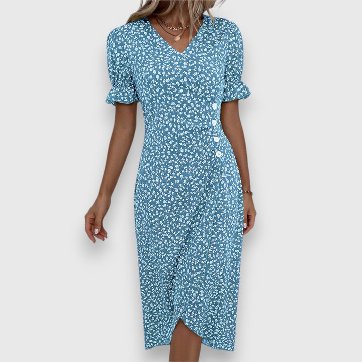 Blue floral dress with ruched sleeves and buttons, woman posing, studio setting.