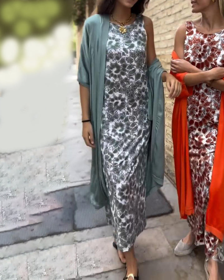 Two people walking on a paved path wearing floral dresses, one in a blue shawl and the other in red.