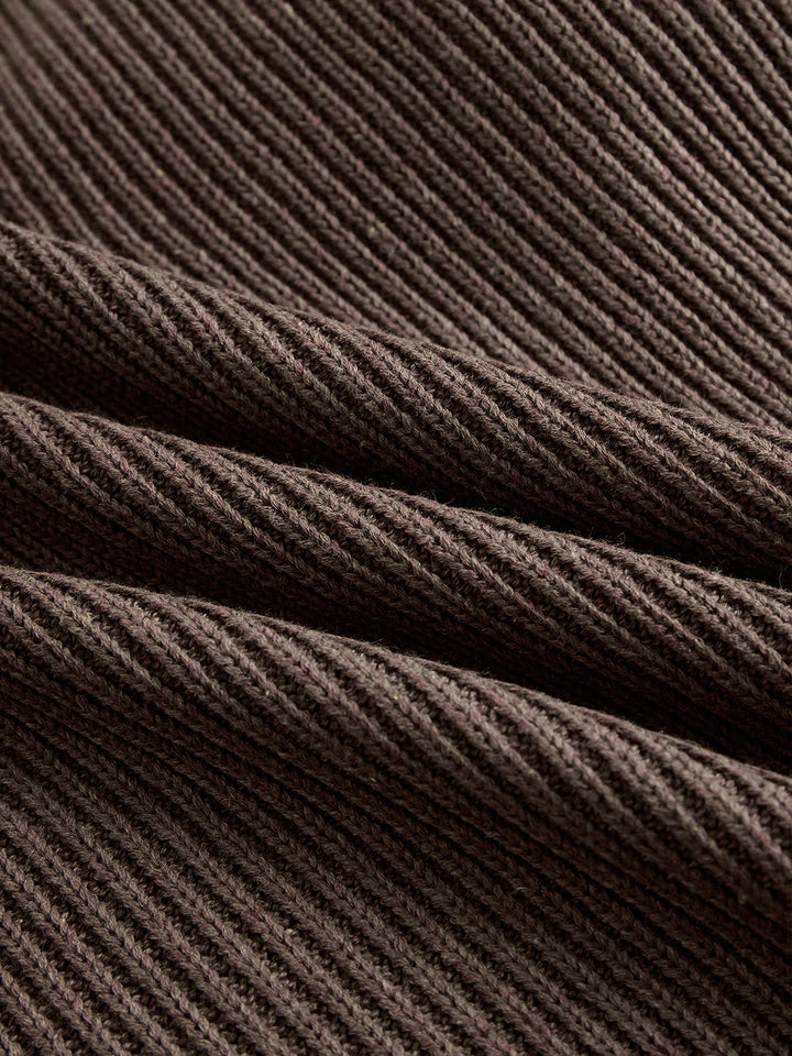 Close-up of dark brown ribbed sweater fabric, showcasing the detailed texture and cozy, soft appearance.