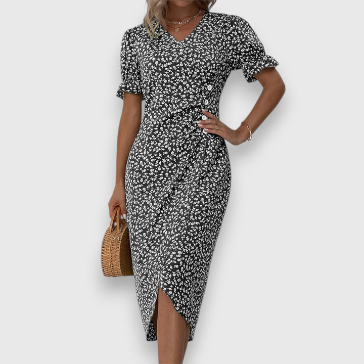 Black floral dress with gathered sleeves and buttons, woman with hand on hip, studio backdrop.