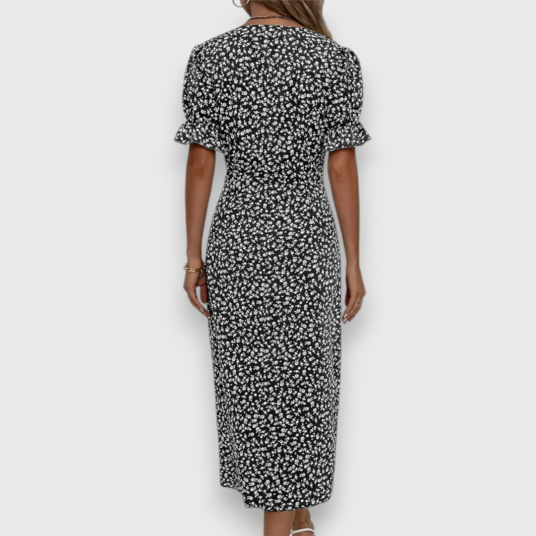 Back view of black floral dress with ruched sleeves, woman standing, studio background.