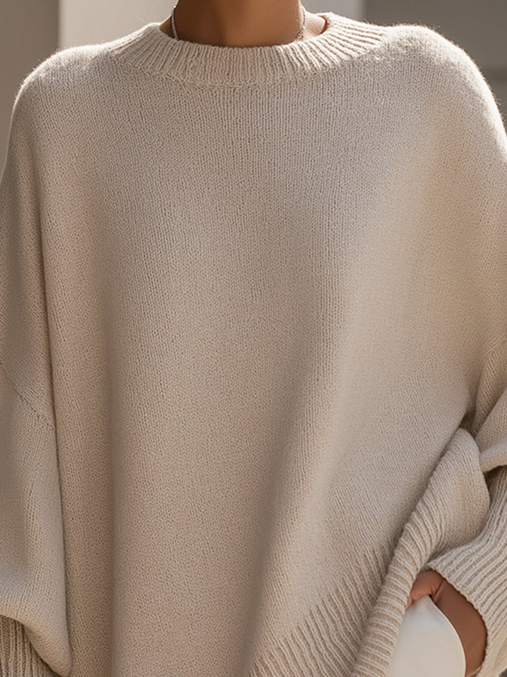 Close-up of a beige sweater showcasing its soft, textured knit and ribbed neckline, in an urban setting.