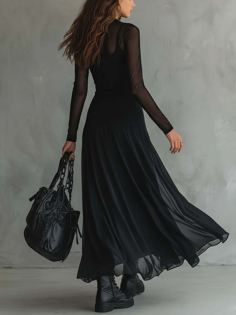 Rear view of woman in a black maxi dress with sheer sleeves, holding a black bag, standing indoors with a textured gray background.