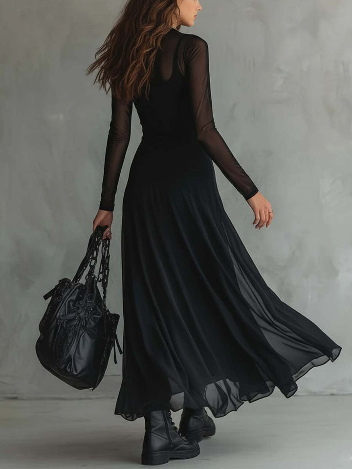 Rear view of woman in a black maxi dress with sheer sleeves, holding a black bag, standing indoors with a textured gray background.