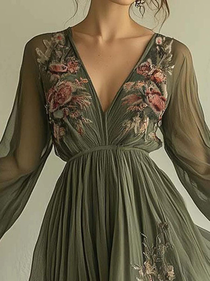 Close-up of elegant chiffon dress bodice in olive green with intricate floral embroidery and deep V-neck indoors.