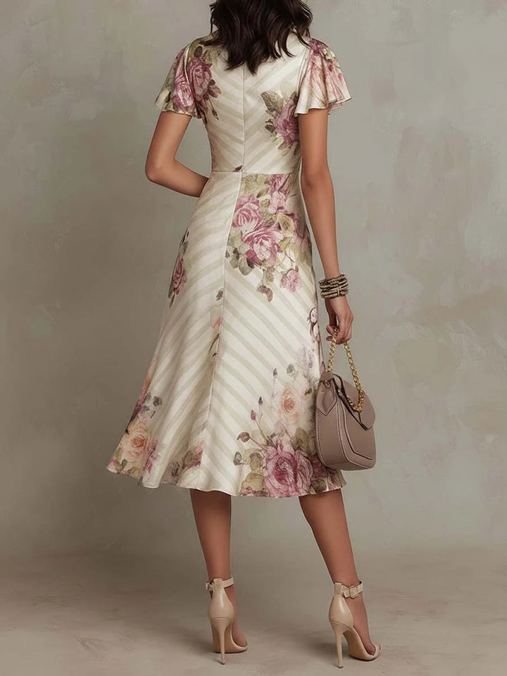 Back view of floral midi dress with flared silhouette and short sleeves in a studio environment.