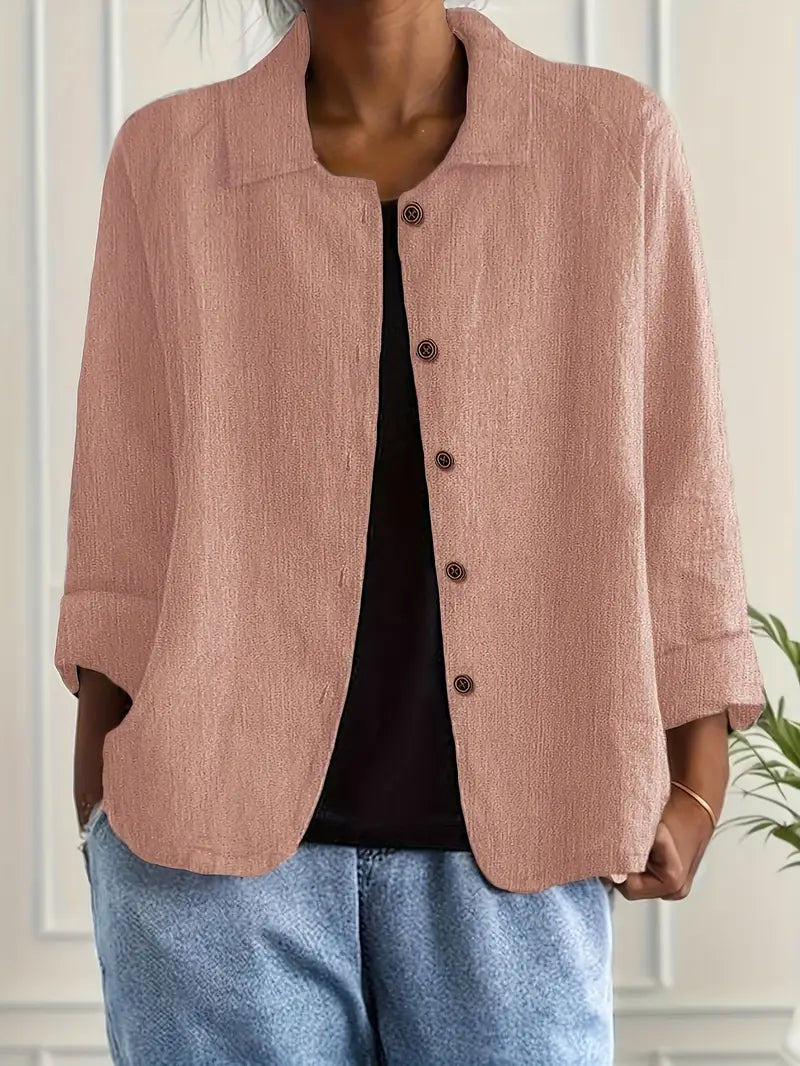 Light brown button-up top with rolled sleeves, worn over black shirt in an indoor setting.