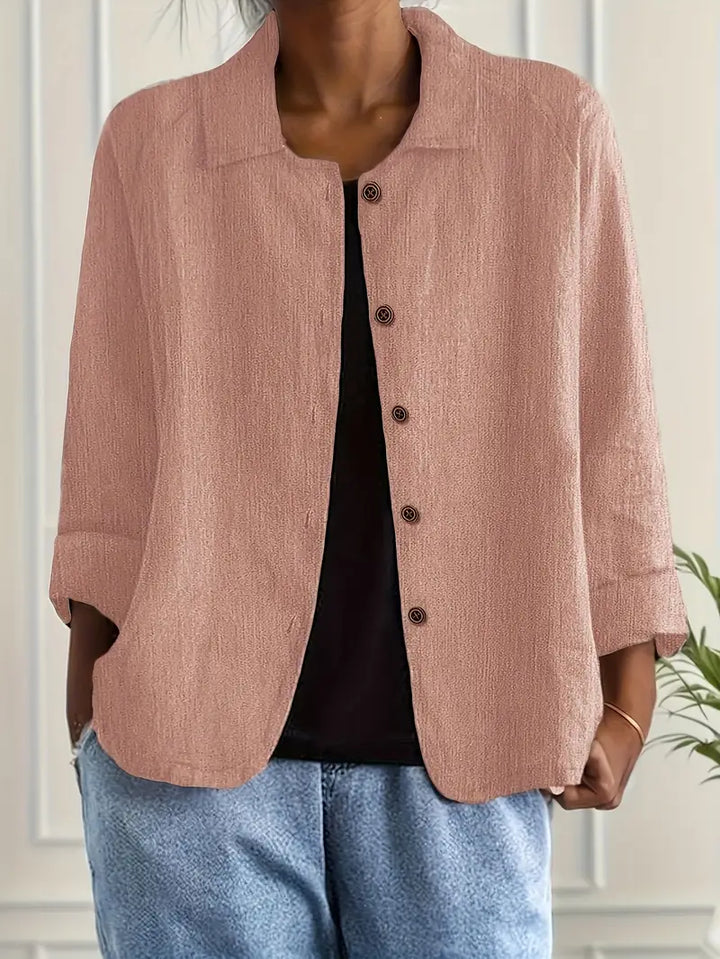 Light brown button-up top with rolled sleeves, worn over black shirt in an indoor setting.