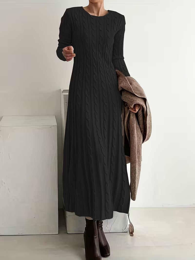 Sophisticated black maxi dress with a textured design, worn with brown boots, set in a clean, indoor space.