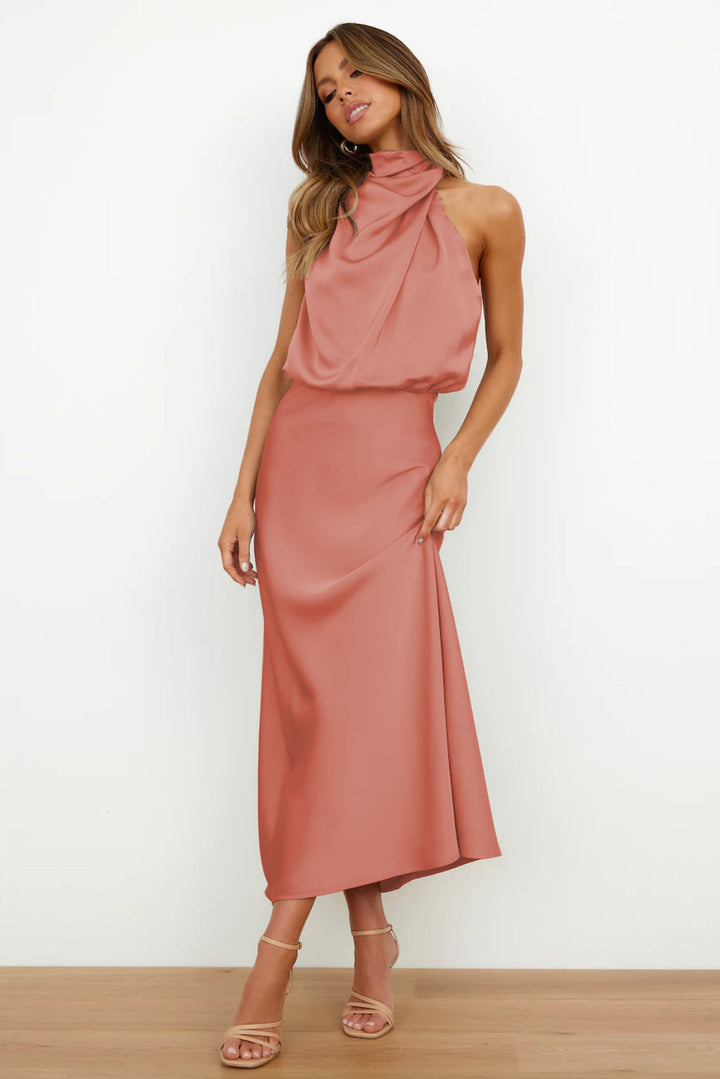 Coral sleeveless halter dress featuring a soft, flowing style in a simple indoor setting.