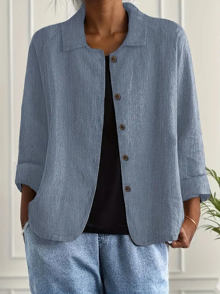 Slate blue button-up top with rolled sleeves, worn over black shirt in an indoor setting.