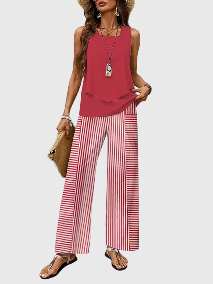 Model in red sleeveless top with layered hem and red striped wide-leg pants. Neutral backdrop.