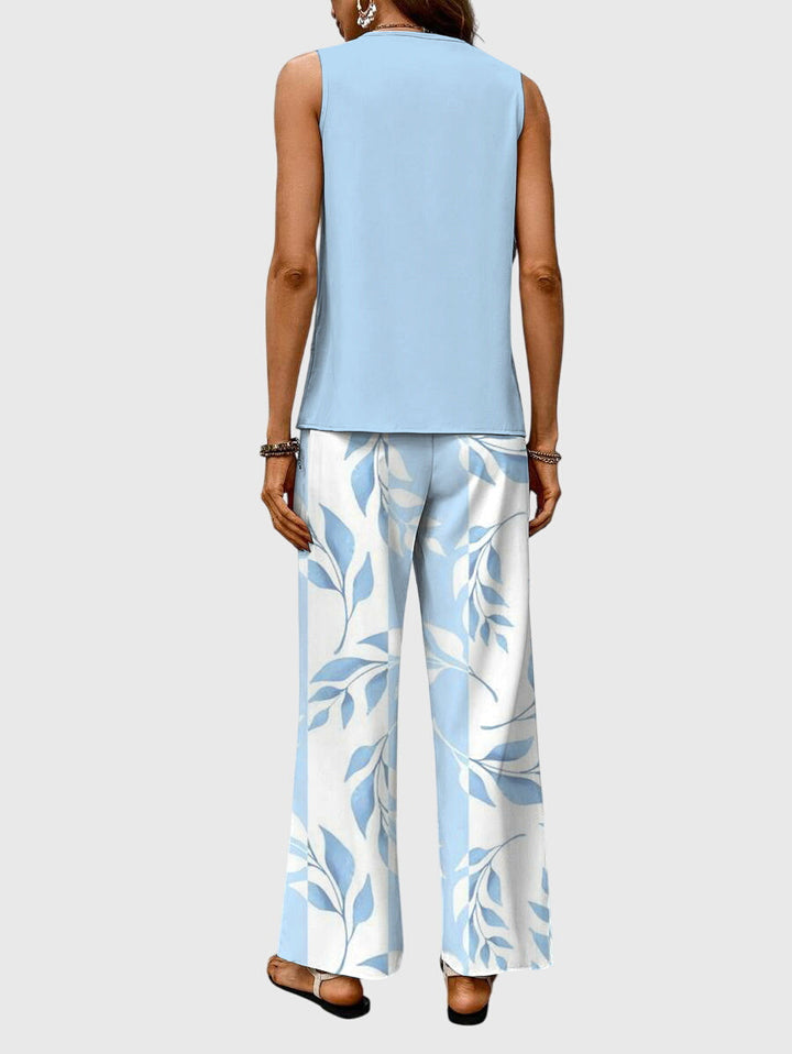 Back view of model in light blue sleeveless top and wide-leg floral pants. Neutral backdrop.