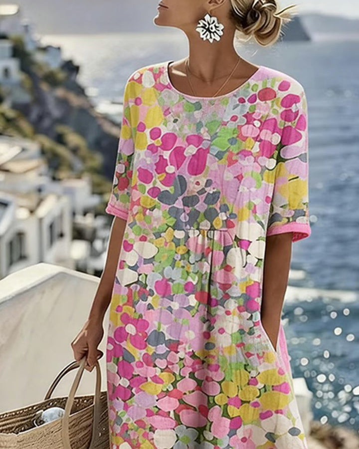 Close-up of woman in floral summer dress, standing on coastal terrace with ocean in background.