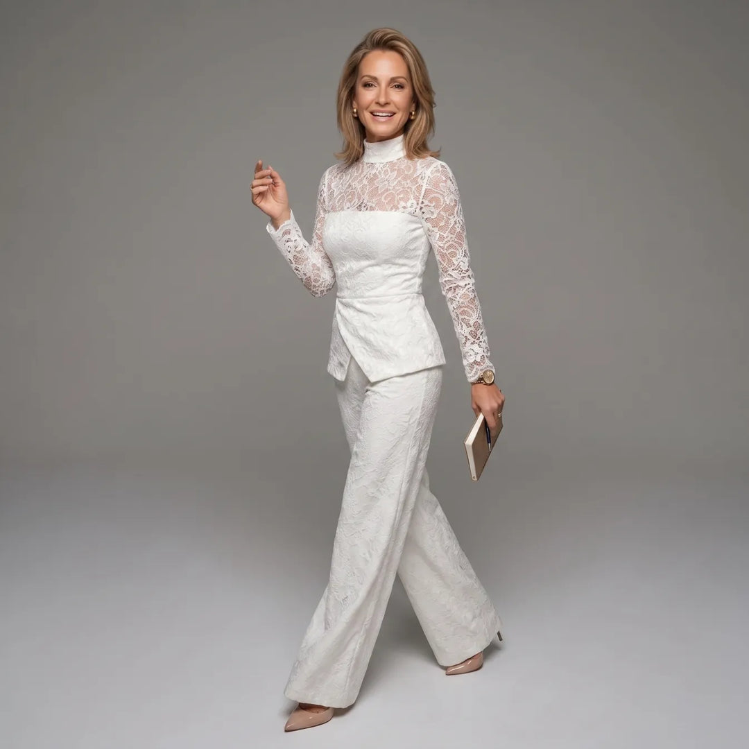 White lace jumpsuit with long sleeves in motion, holding a book, on gray studio backdrop.