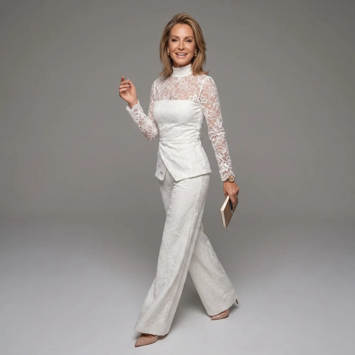 White lace jumpsuit with long sleeves in motion, holding a book, on gray studio backdrop.