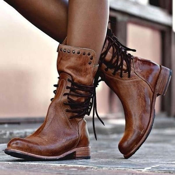 Brown vintage lace-up boots with studded details, worn by a model in an urban setting.