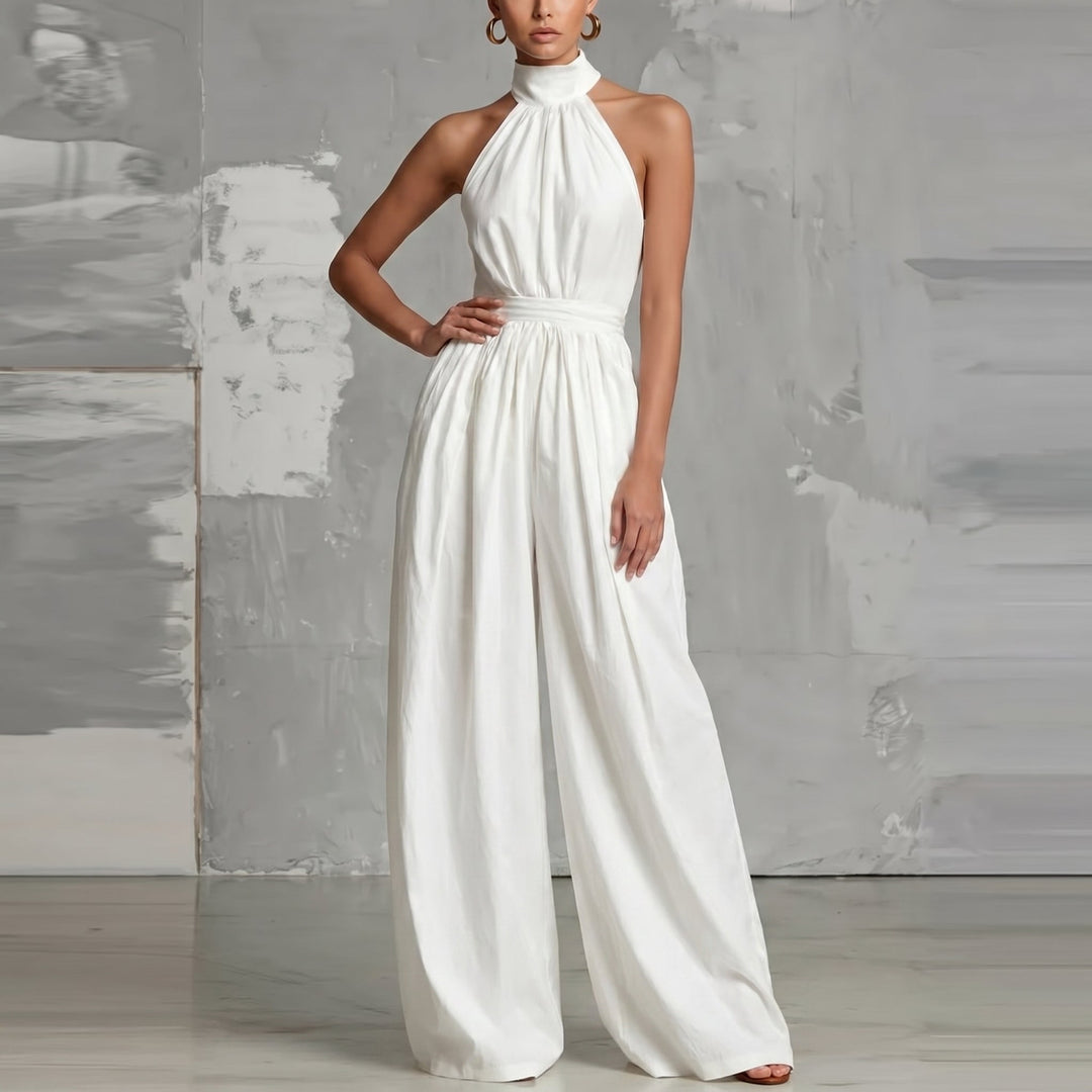 Elegant white halter-neck jumpsuit with wide legs, posed in a modern studio environment.
