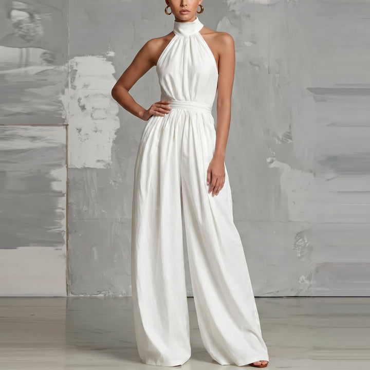 Elegant white halter-neck jumpsuit with wide legs, posed in a modern studio environment.