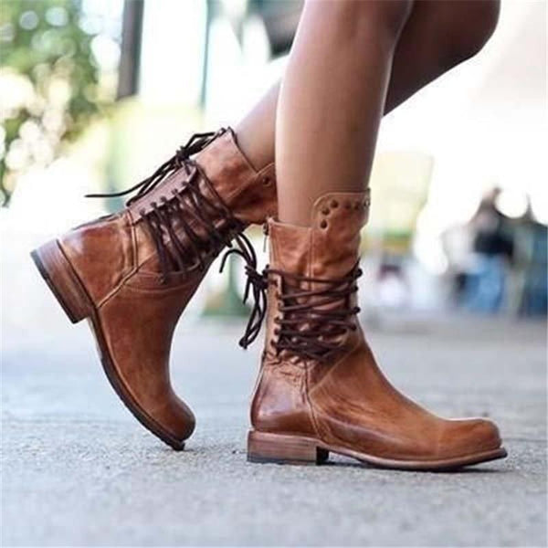 Brown vintage lace-up boots on a model standing on a sidewalk, sunlit urban background.