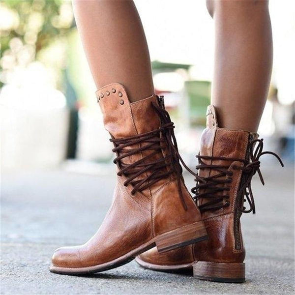 Side view of brown lace-up boots with studs, worn outdoors on pavement.