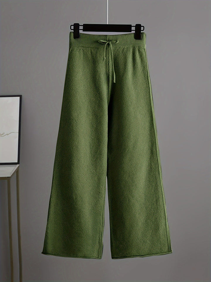 Olive green knit pants with a relaxed fit and drawstring on a hanger, gray background.