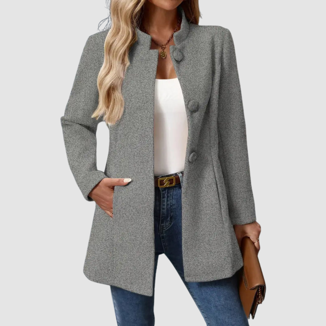 Gray jacket with large buttons, worn over white top and jeans, holding a clutch against a plain background.