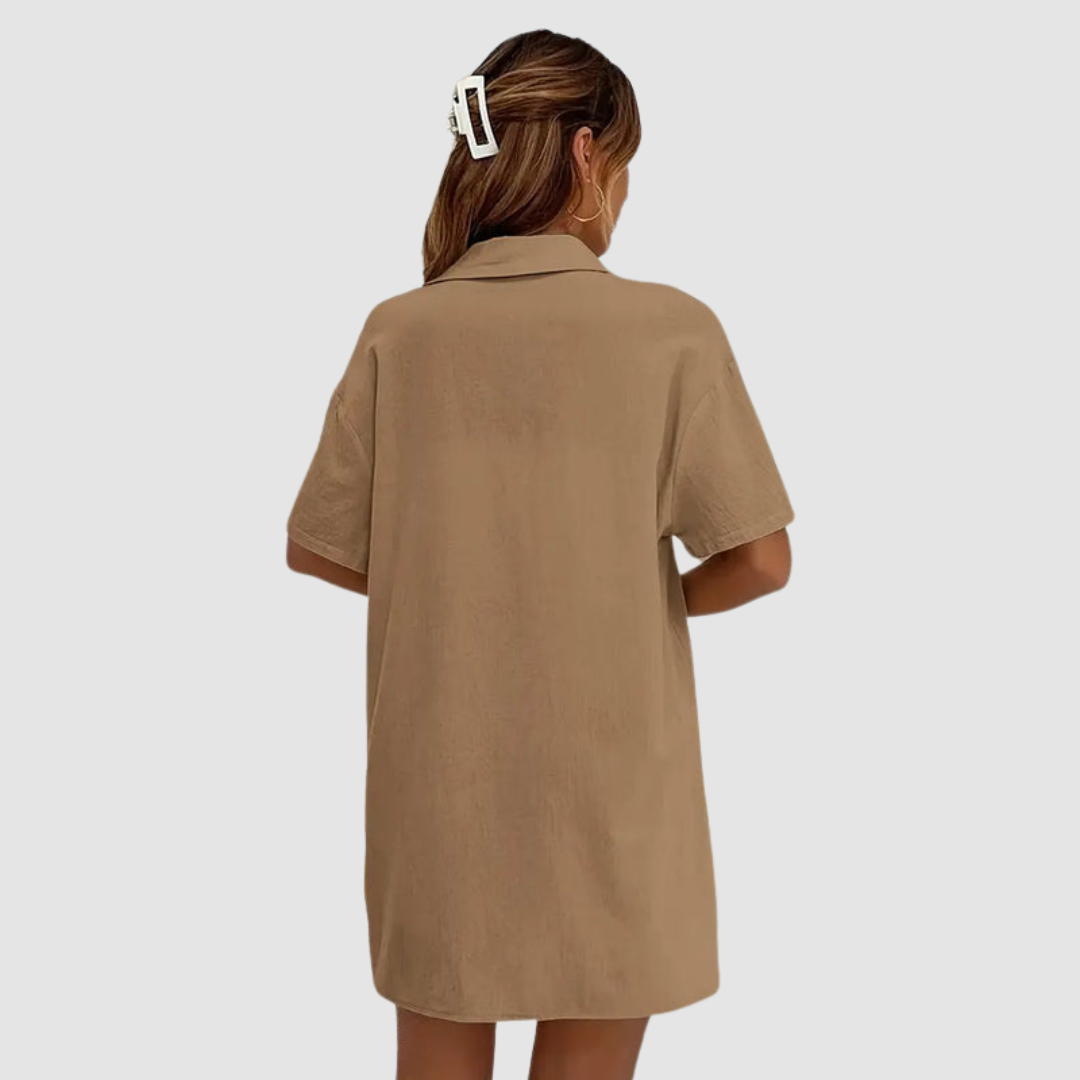 Back view of woman in brown button-up dress, hair clipped, against a studio background.