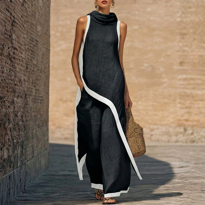 Elegant black sleeveless outfit with white trim, worn by a person carrying a woven bag, outdoor brick wall backdrop.