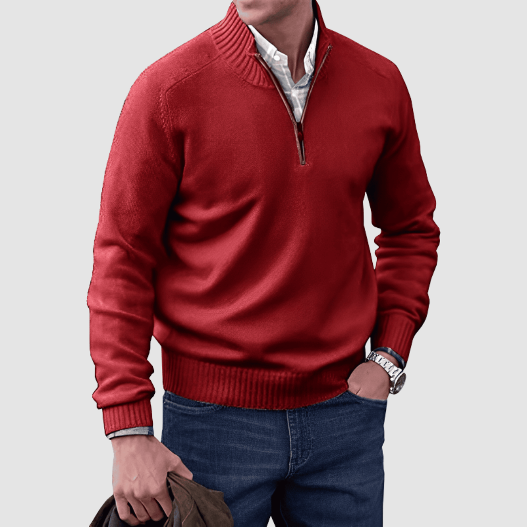 Model in red zip pullover with ribbed collar and cuffs, holding a jacket. Paired with jeans, set against a plain background.
