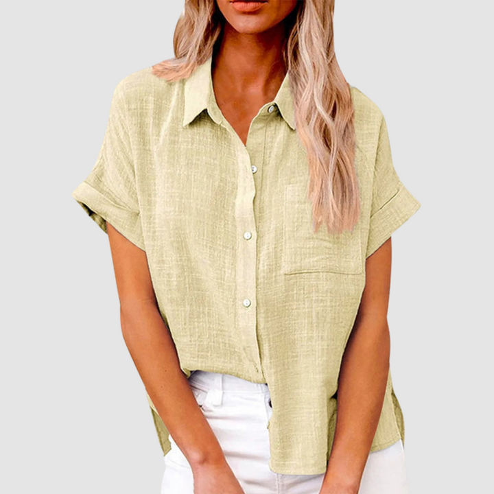 Light green casual blouse with short sleeves and front buttons, worn in white jeans. Studio background.