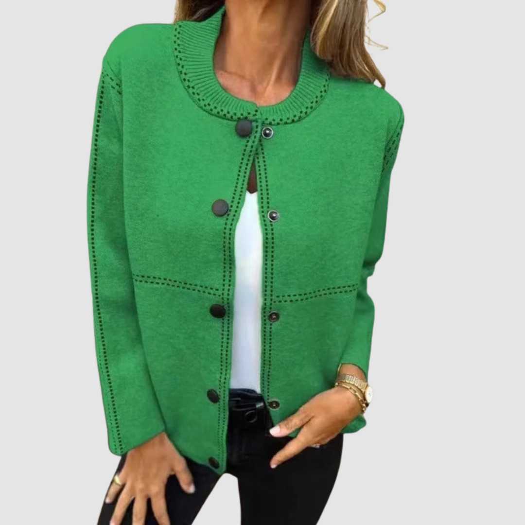 Green jacket with round collar, button closure, worn over white top and black pants in a studio setting.