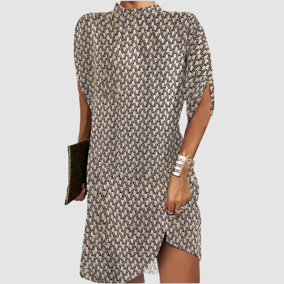 Patterned knee-length dress with black and beige design, loose fit, high neckline, accessorized with gold bangles and clutch on gray.