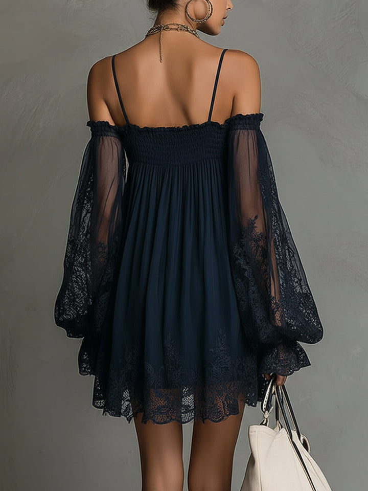 Back view of navy off-shoulder dress featuring lace sleeves and hem, paired with a white tote in studio setting.