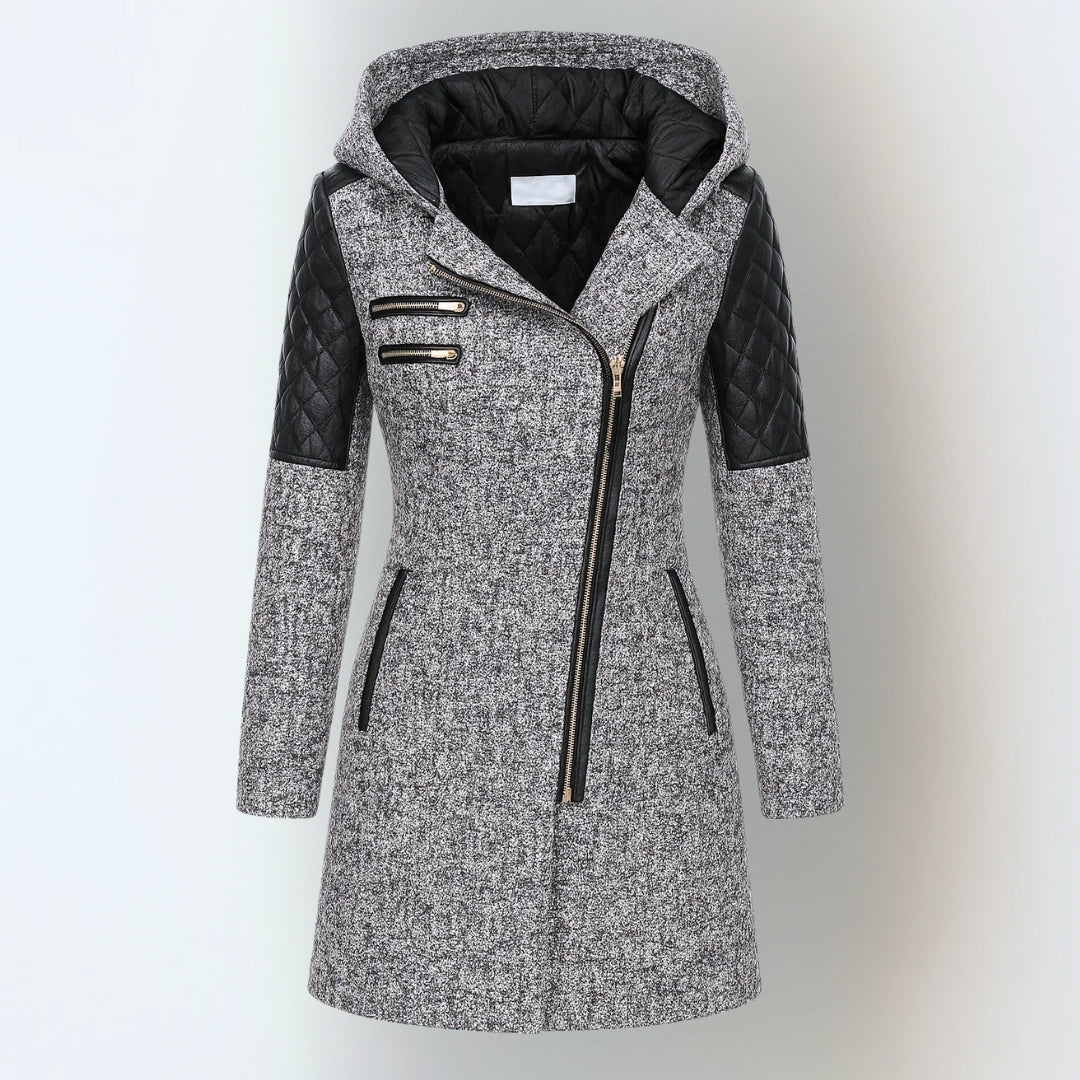 Grey hooded winter jacket with black quilted accents and asymmetrical zipper, studio background.