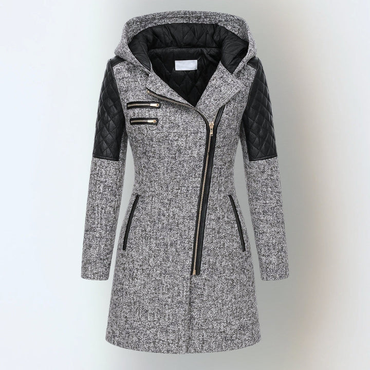 Grey hooded winter jacket with black quilted accents and asymmetrical zipper, studio background.