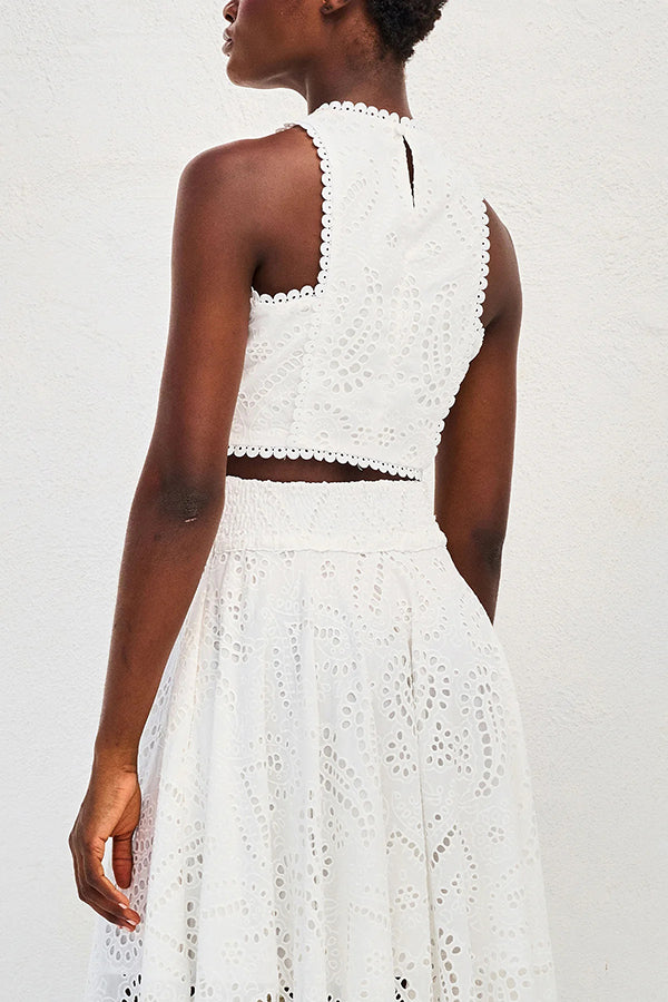 Back view of a model in a white embroidered top and high-waist maxi skirt against a white background.