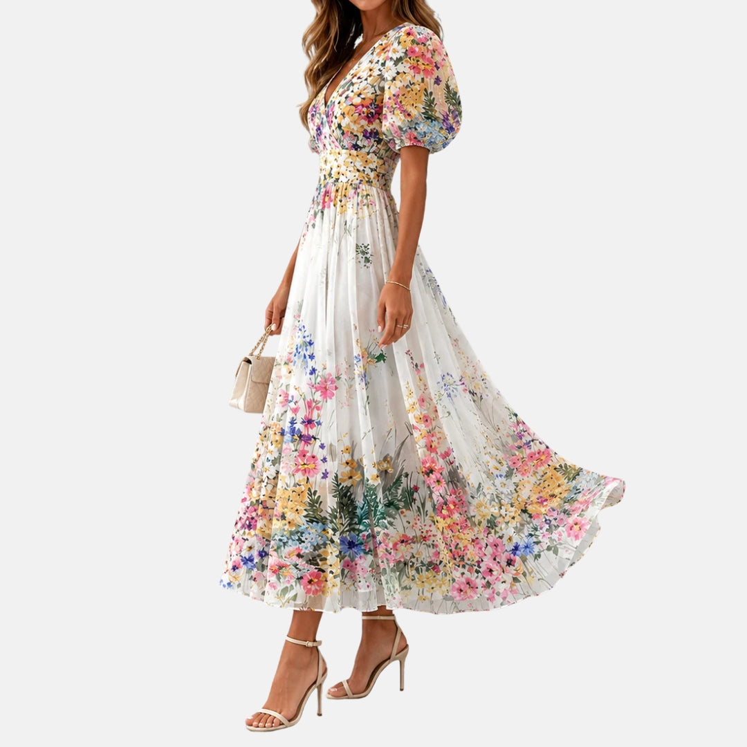 Side view of floral midi dress with puff sleeves in a studio. Model holds a beige purse.