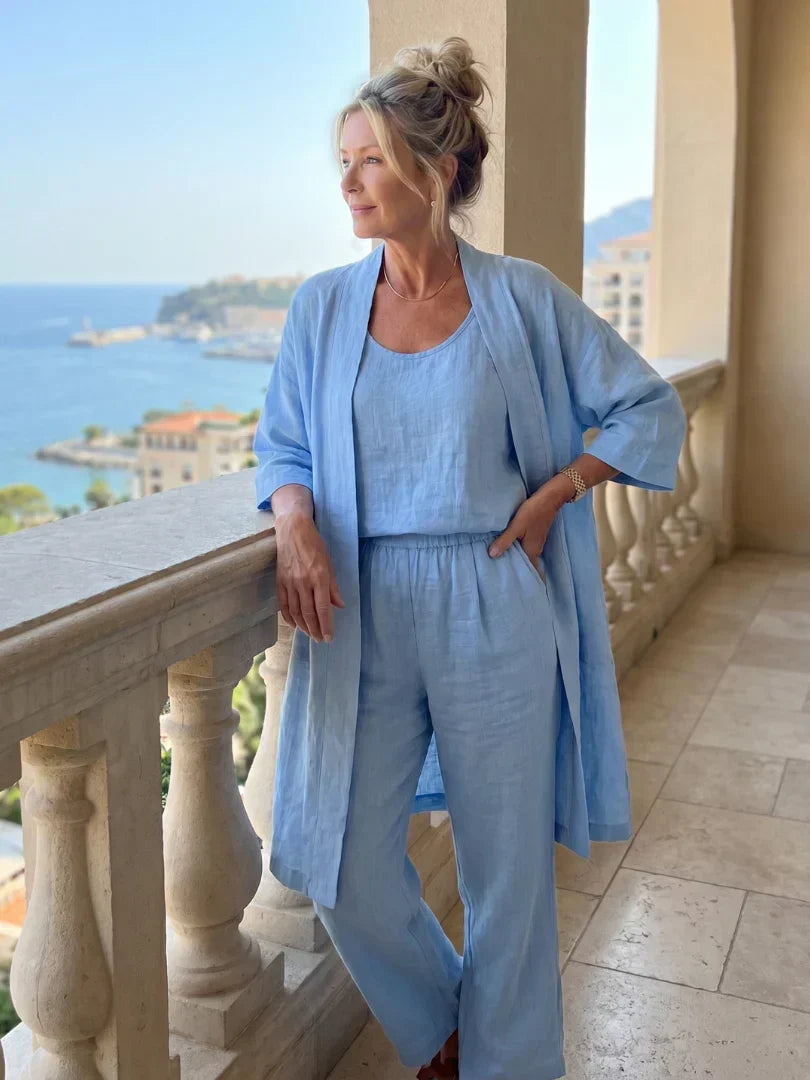 Woman in light blue outfit on balcony with sea view, elegant and relaxed.
