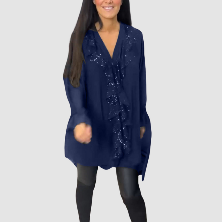 Dark blue blouse with ruffle embellishments, complemented by leggings in a studio setting.