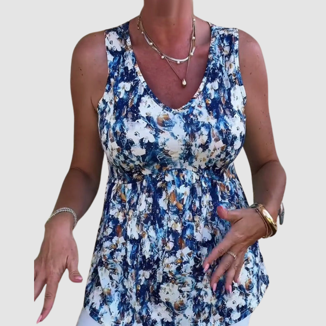 Woman gesturing in a blue and white abstract pattern sleeveless top in a studio setting.