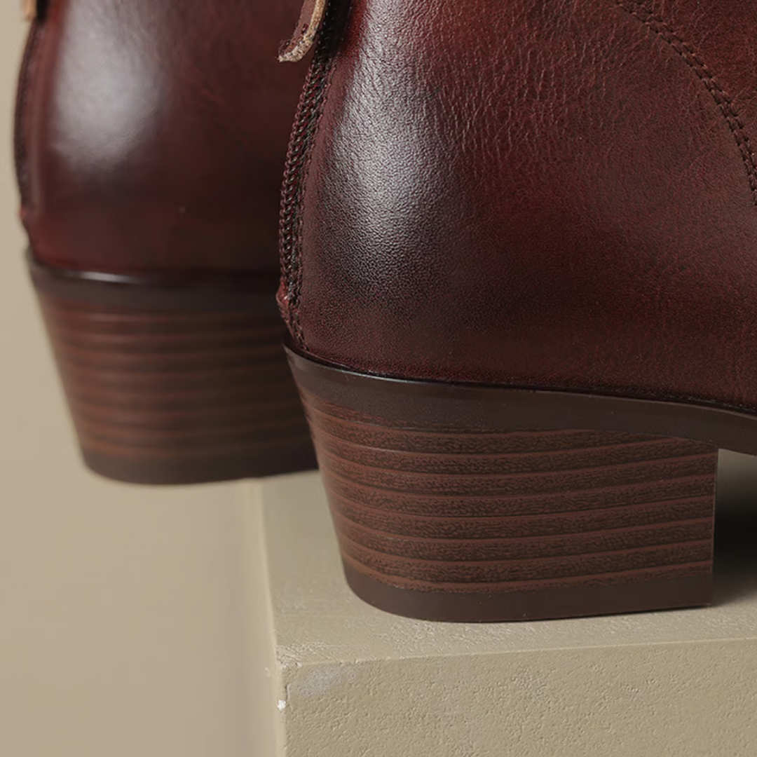 Close-up of stacked block heels on brown ankle boots, shown on a textured platform.