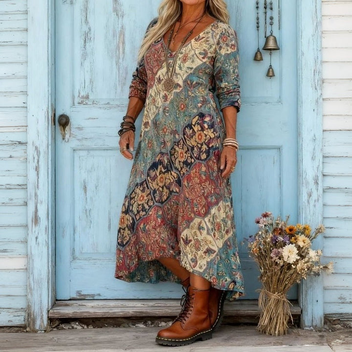 Flowy printed maxi dress with colorful designs, worn outdoors against a vintage blue door with flower bouquet.