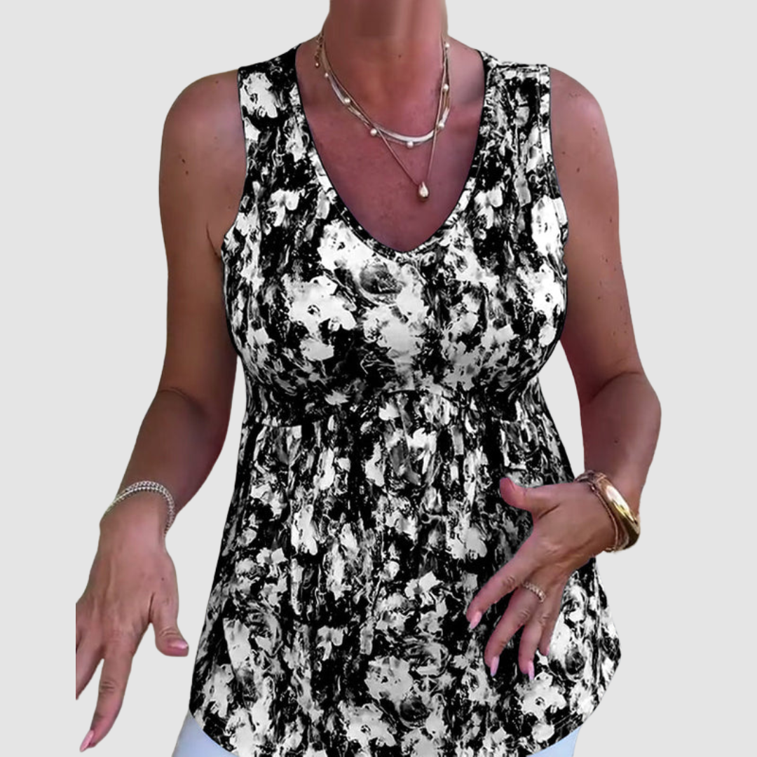 Woman gesturing while wearing a black and white abstract pattern sleeveless top in a studio setting.