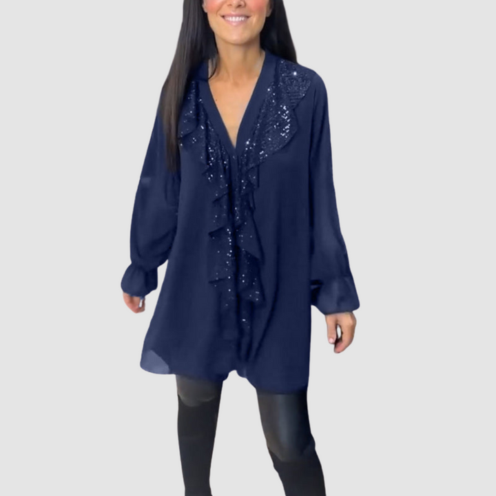 Navy ruffled blouse with glimmering accents, matched with leggings in a minimal studio setting.