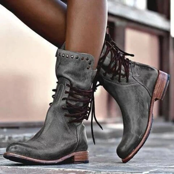 Gray lace-up boots with dark laces, worn by a model in an urban setting.