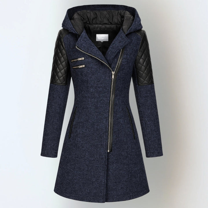 Navy blue hooded winter jacket with black quilted shoulders and asymmetrical zipper, studio background.