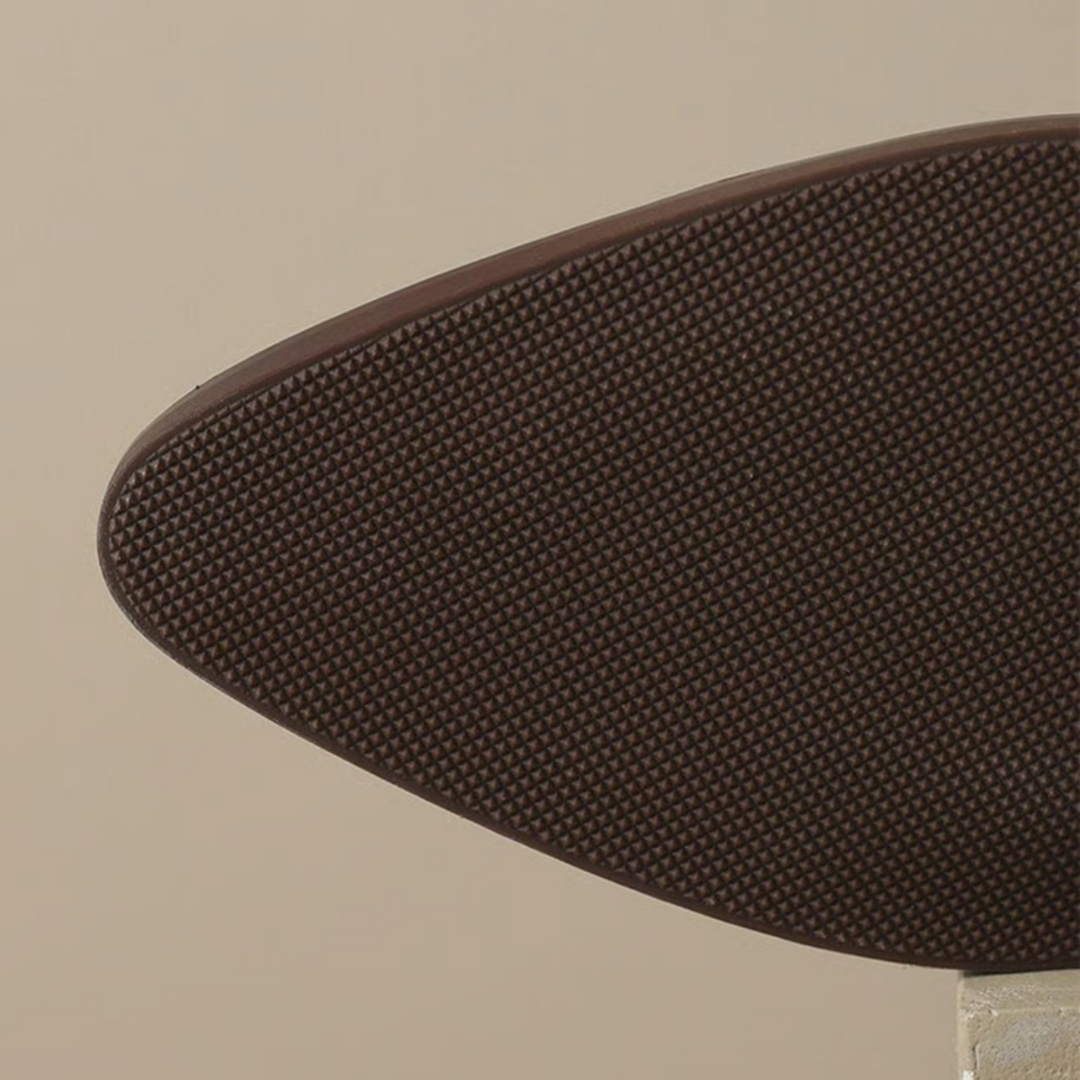 Close-up of brown ankle boot sole, showcasing textured grip on a neutral background.