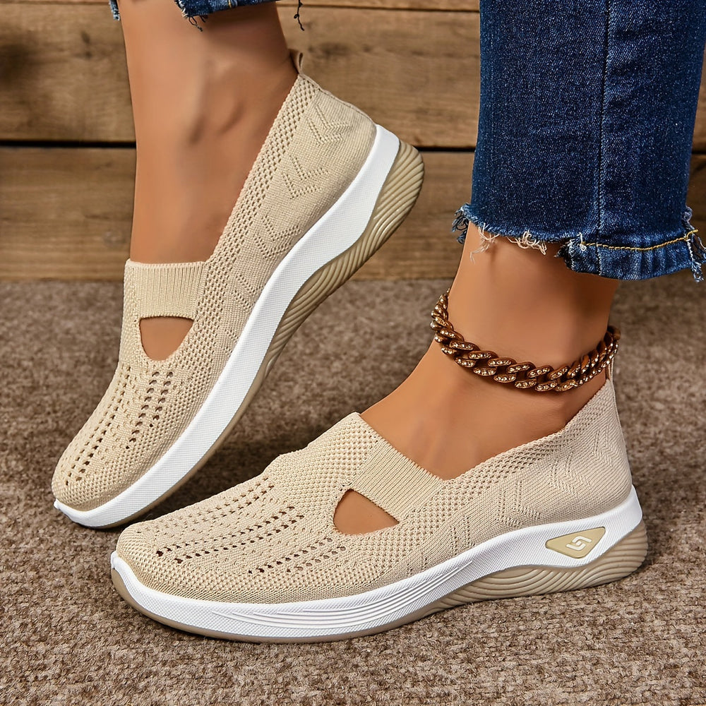Beige non-slip orthopedic shoes worn with anklet, denim jeans on carpeted floor.