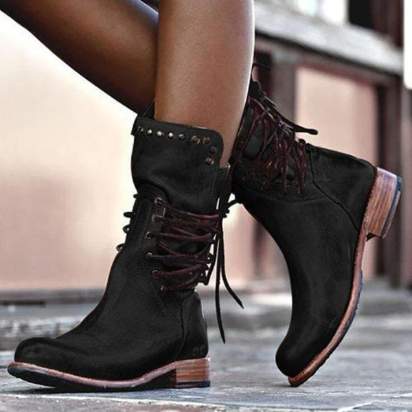 Black vintage lace-up boots with stud details, modeled in front of a window.